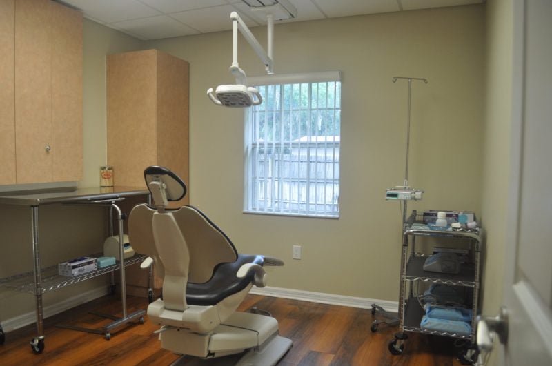 Dental operatory with patient chair, surgical light, and wooden cabinets
