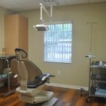 Dental operatory with patient chair, surgical light, and wooden cabinets